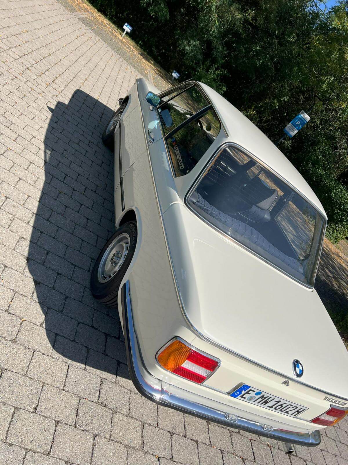 Dieses Foto zeigt den BMW 1602, einen Oldtimer aus dem Jahr 1975. Das Fahrzeug kommt in der Farbe Chamonix Weiß mit blauen Kunstleder. Der Wagen wurde bereits restauriert, hat TÜV und verfügt über einen Vierzylinder-Reihenmotor mit 1,6 L Hubraum. Bieten Sie jetzt mit!